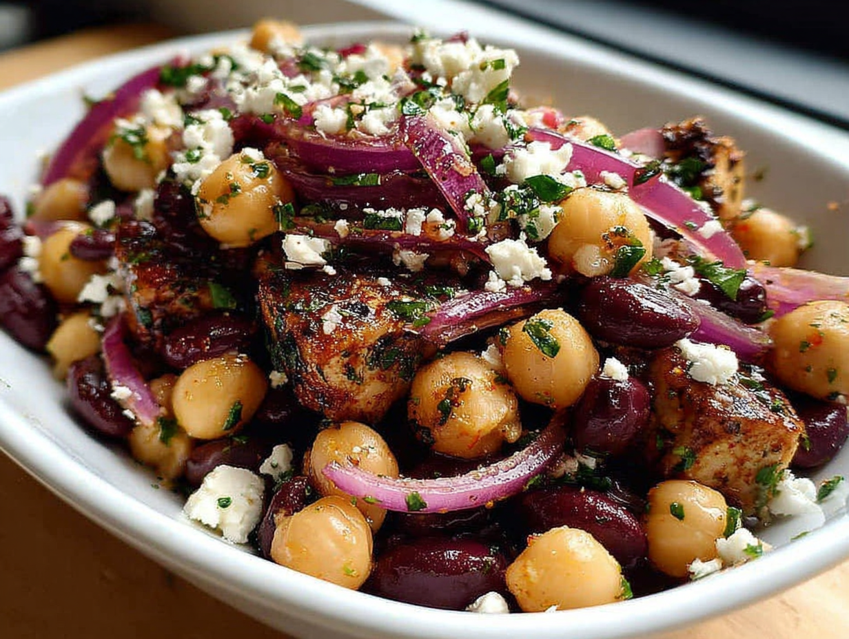 A close-up of Divorce Salad in a white bowl, showing chickpeas, black beans, feta, and red onion.