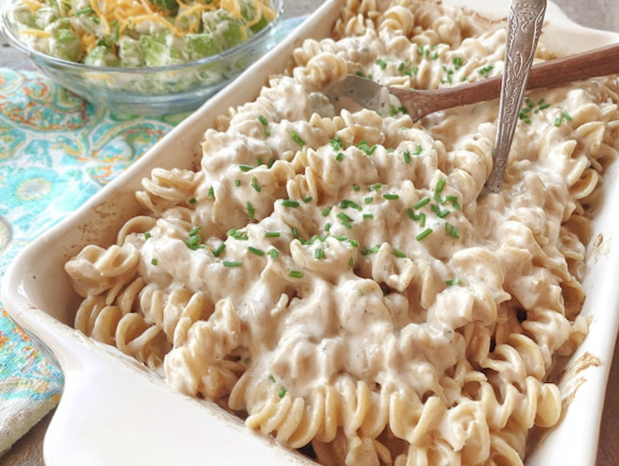 A white bowl filled with Polish noodles with sour cream and onion, garnished with fresh chives.